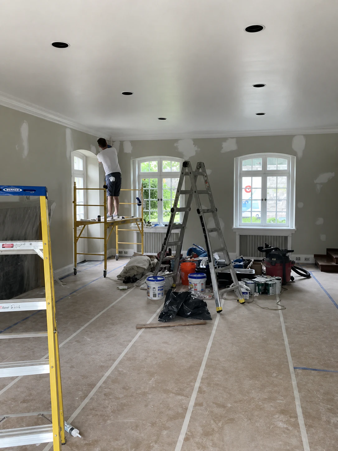 Interior painting project in progress with protected floors and work ladders