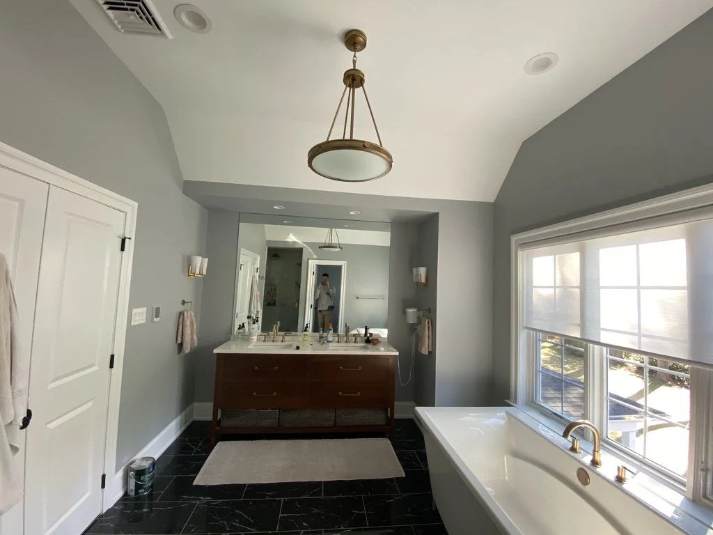 Renovated bathroom with gray walls, dark tile, and a freestanding tub