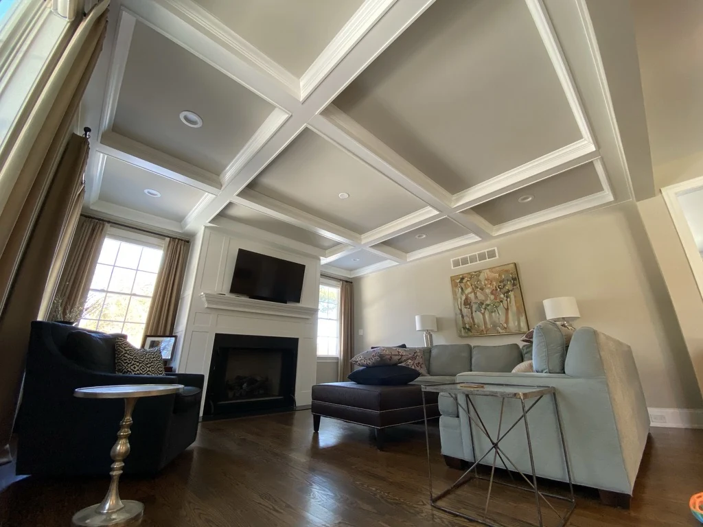 Finished living room with coffered ceiling, fireplace, and hardwood floors