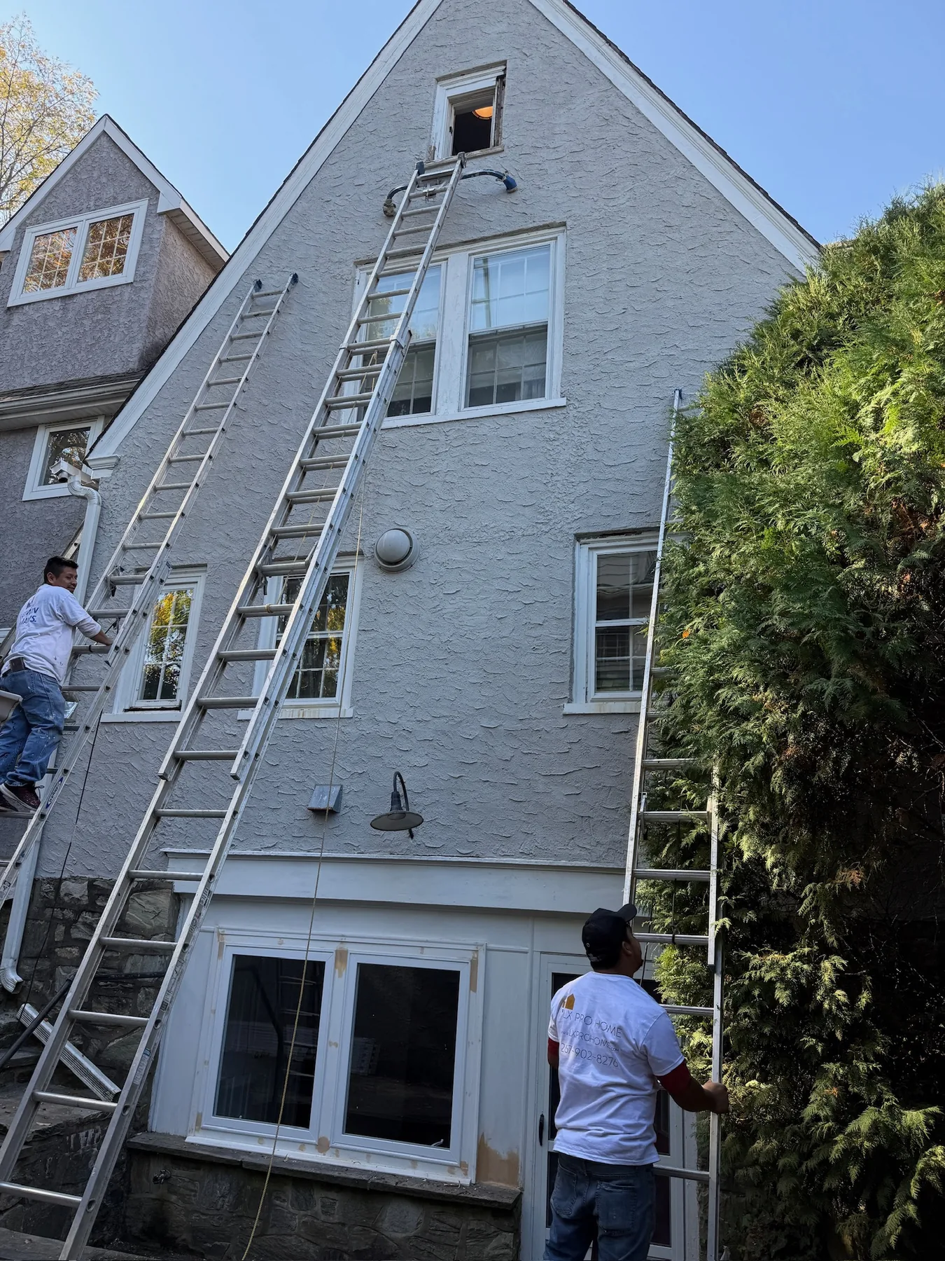 Exterior painting crew working on upper-story trim