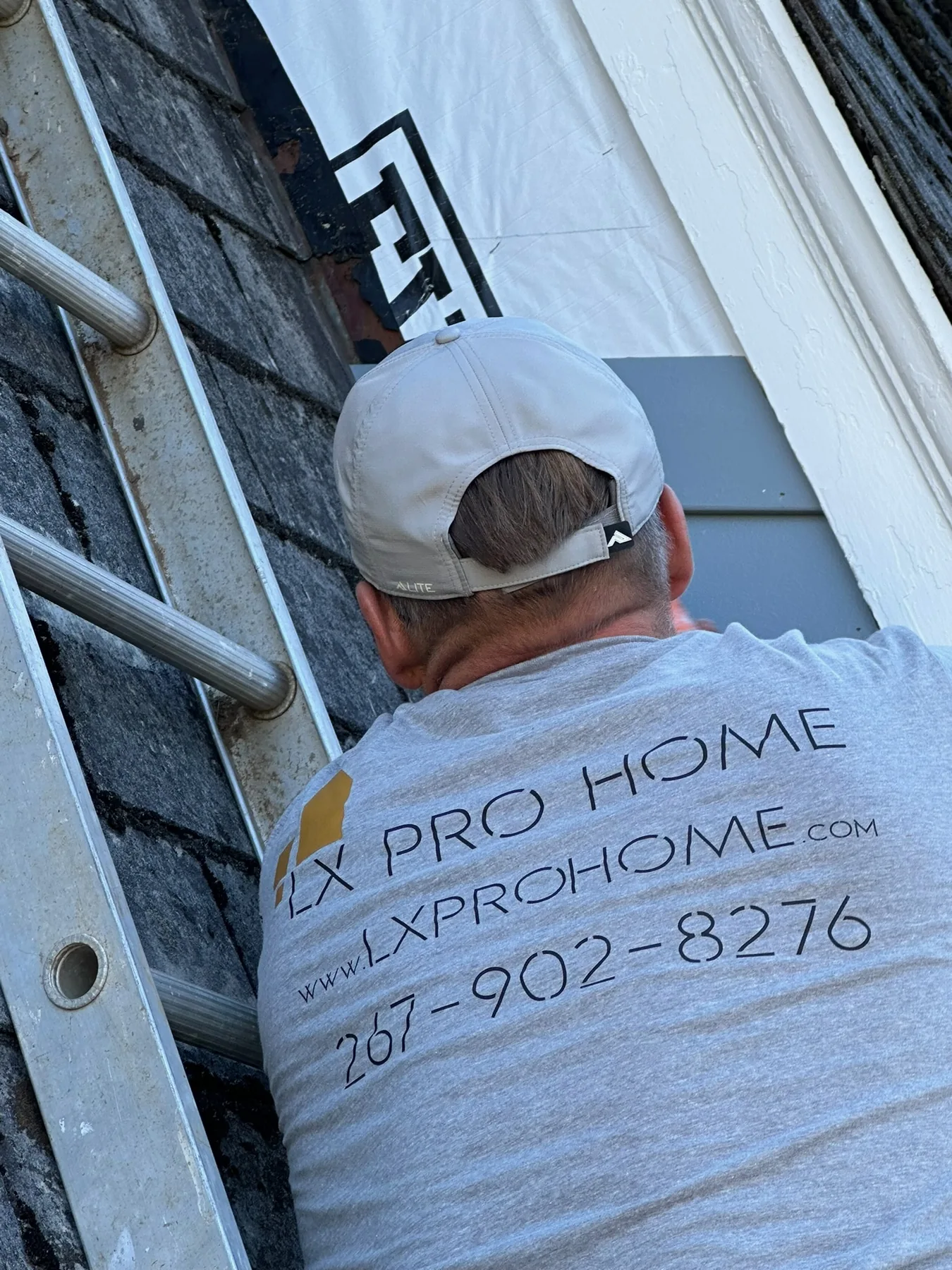 Exterior painter applying a finish to upper trim