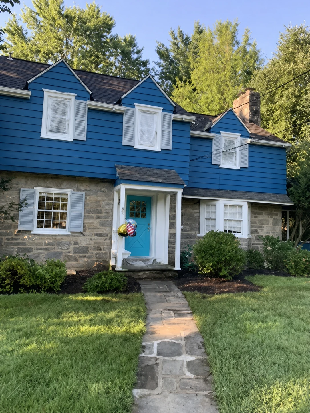 Blue and stone home exterior with white shutters and a turquoise front door